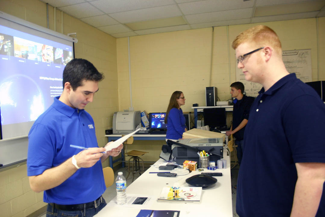 Click to enlarge,  Cree, Inc., recruiter Tyler Bennett (left) looks over the resume of Central Carolina Community College laser and photonics student Eric West, of Angier, following a Feb. 26 presentation by Bennett and other Cree employees at the college's Harnett County Campus, in Lillington. In the background, Cree recruiter Amy Brandt (left) talks with laser and photonics student Caleb Cardin, of Garner. Cree, headquartered in Durham, is an international leader in research, innovation and production in light-emitting diode (LED) and radio frequency (RF) technologies. The Cree representatives said graduates of the college's laser and photonics, electronics engineering, and computer engineering programs are well prepared to work at their company. For more information about engineering technologies programs offered at CCCC, visit www.cccc.edu. 