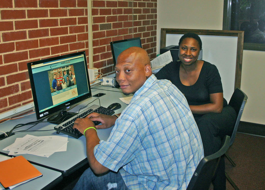 Click to enlarge,  Spencer Bridges (front), of Sanford, a Central Carolina Community College Business Administration major, works with Torry Reynolds, lead success coach, at the college's new College Success Center. The college piloted the program during the spring semester and CCCC will now offer College Success Center services to students at its campuses in Chatham, Harnett and Lee counties. Seven success coaches, in partnership with faculty and staff, will work proactively with students to improve their success in course completion and graduation. The College Success Center is located in the Hockaday Hall at the Lee County Campus, in Sanford; in the Miriello Building at the Harnett County Campus, in Lillington; and in the Health/Continuing Education Building at the Chatham County Campus, in Pittsboro. For more information about the College Success Center and its programs, go to   or contact the Center at 919-775-5401, extension 7485.  