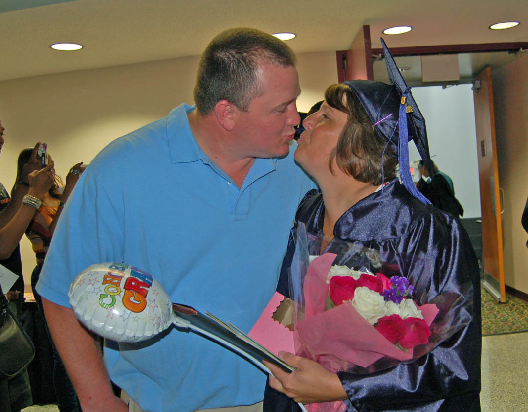 Click to enlarge,  Chatham County resident Tina Thomas (right) receives a congratulatory kiss from her husband, Jason Thomas, following Central Carolina Community College's College and Career Readiness graduation ceremony June 20 at the Dennis A. Wicker Civic Center. A total of 246 students earned Adult High School or GED diplomas. For more information on the programs, visit www.cccc.edu or contact a College and Career Readiness office: Chatham County - 919-545-8661 or 919-545-8028, Harnett County - 910-814-8974, or Lee County - 919-777-7707. Para mas informacion en espanol - 919-545-8667.  