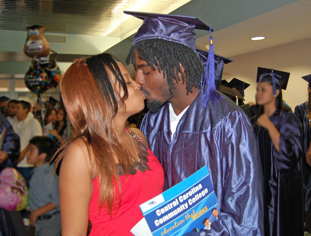 Click to enlarge,  Janine McNeil, of Harnett County (left) gives a congratulatory kiss to her boyfriend, Brandon Huffman, following Central Carolina Community College's College and Career Readiness graduation exercises June 20 at the Dennis A. Wicker Civic Center. A total of 246 students earned Adult High School or GED diplomas. For more information on the programs, visit www.cccc.edu or contact a College and Career Readiness office: Chatham County - 919-545-8661 or 919-545-8028, Harnett County - 910-814-8974, or Lee County - 919-777-7707. Para mas informacion en espanol - 919-545-8667.  