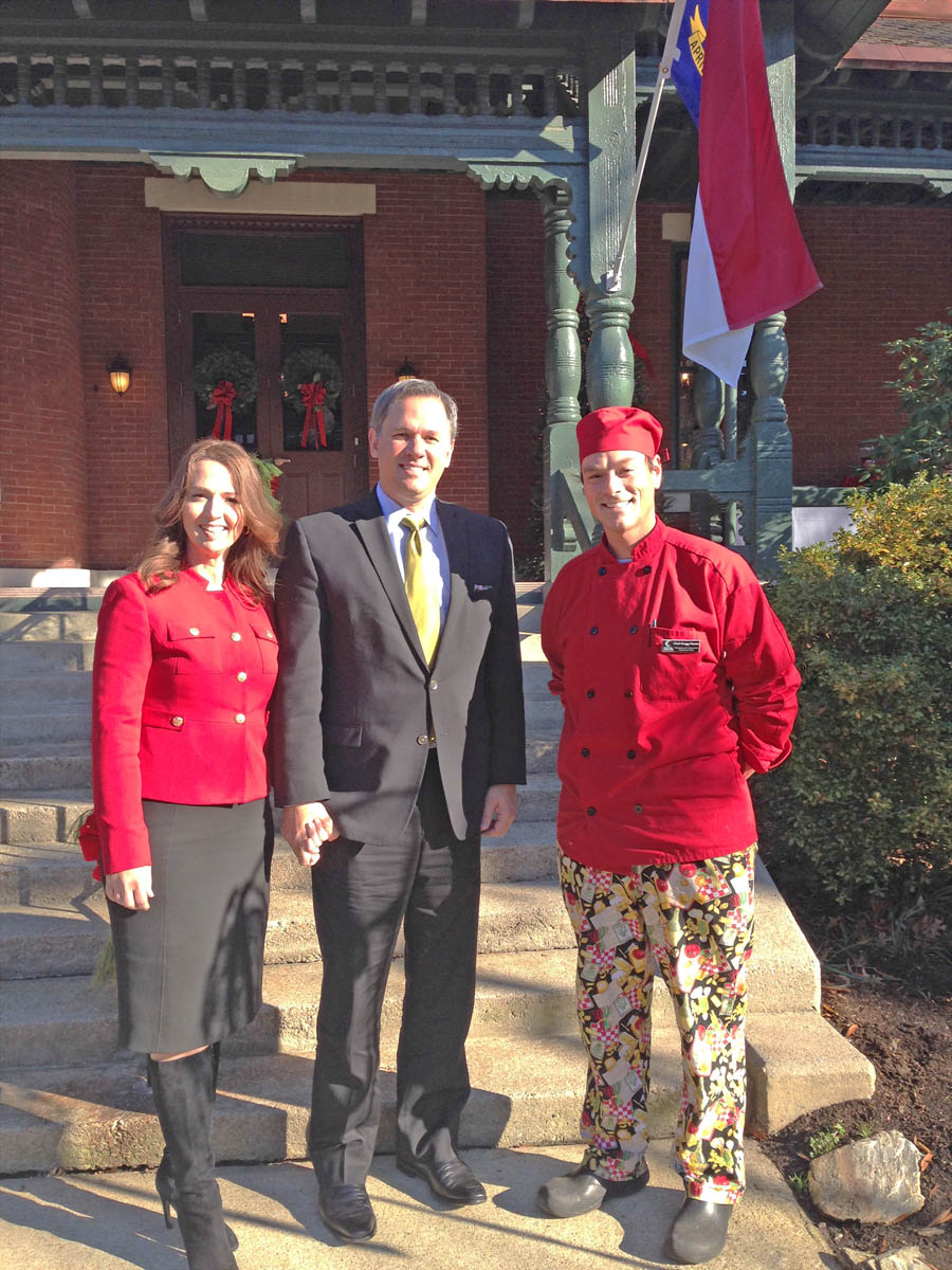 Click to enlarge,  North Carolina Lt. Gov. Dan Forest (center) and his wife, Alice (left) hosted a Christmas Open House Dec. 12 at the Lieutenant Governor's mansion, the historic Hawkins-Hartness House, in Raleigh. Chef Gregg Hamm (right), director of Central Carolina Community College' Hospitality and Culinary Arts Program, and his Culinary Arts students were invited to provide the refreshments for the event. The students prepared 1,000 cookies using wholesome ingredients such as molasses, local honey, whole grains, gluten-free flours, and local eggs. They also prepared local apple cider for the enjoyment of the visitors. Hamm said it was an honor to be asked to do the event and an exciting experience for the students. For more information about culinary arts training at CCCC, visit www.cccc.edu/culinaryarts or contact Hamm at 919-545-8070. 