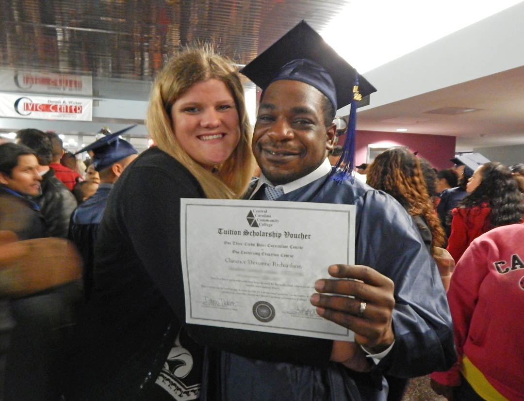 Click to enlarge,  Clarence Richardson (right) and his wife, Hailey, are all smiles after he received his GED at Central Carolina Community College's Adult High School/General Educational Development exercises Jan. 16 at the Dennis A. Wicker Civic Center. Richardson holds his Tuition Scholarship Voucher from CCCC for a free class. He has already enrolled for the spring semester and is studying electrical engineering technology. For more information about Central Carolina Community College's AHS/GED programs, visit www.cccc.edu or contact a College and Career Readiness coordinator: Chatham County, 919-545-8661 or dloges@cccc.edu; Harnett County, 910-814-8972 or mmcgee@cccc.edu; or Lee County, 919-777-7703 or esmith@cccc.edu. Para mas informacion en espanol - 919-545-8667 or jherbon@cccc.edu. 