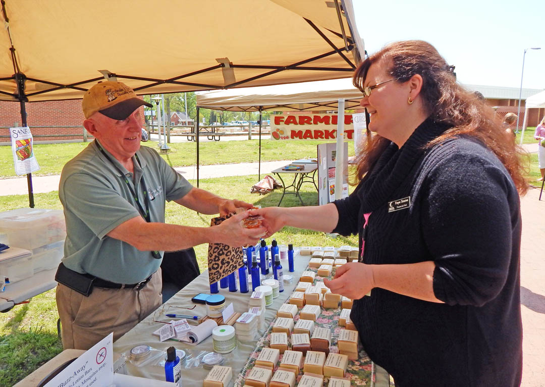 Click to enlarge,  Central Carolina Community College's chapter of the Phi Beta Lambda Honor Society hosted a mini-Farmers Market at the college's Lee County Campus April 22 in celebration of Earth Day. Josh Marshburn (left), owner of Garden of Eden Specialty Soaps, in Sanford, sells some of his handmade goat milk and vegan soaps to Faye Stone, CCCC Financial Aid assistant. Earth Day has been celebrated internationally since 1971 and is intended to raise awareness of the importance of protecting the environment and living sustainably. For information on clubs and programs at Central Carolina Community College, visit www.cccc.edu. 