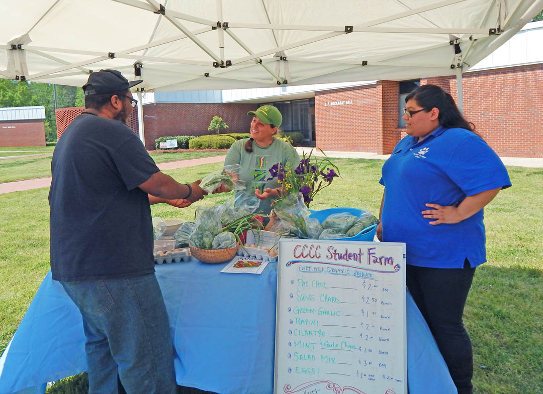 Click to enlarge,  Central Carolina Community College's chapter of the Phi Beta Lambda Honor Society hosted a mini-Farmers Market at the college's Lee County Campus April 22 in celebration of Earth Day. Organically grown produce from CCCC's Student Farm at the Chatham County Campus attracted the interest of visitors during the event. Hillary Heckler (center), Student Farm manager, talks about the vegetables grown there with CCCC broadcasting student Adam Belcher (left), of Snow Camp, and Monica Sagastume-Ceron, of Sanford, the CCCC Student Government Association's liaison to Phi Beta Lambda. Earth Day has been celebrated internationally since 1971 and is intended to raise awareness of the importance of protecting the environment and living sustainably. For information on clubs and programs at Central Carolina Community College, visit www.cccc.edu. 