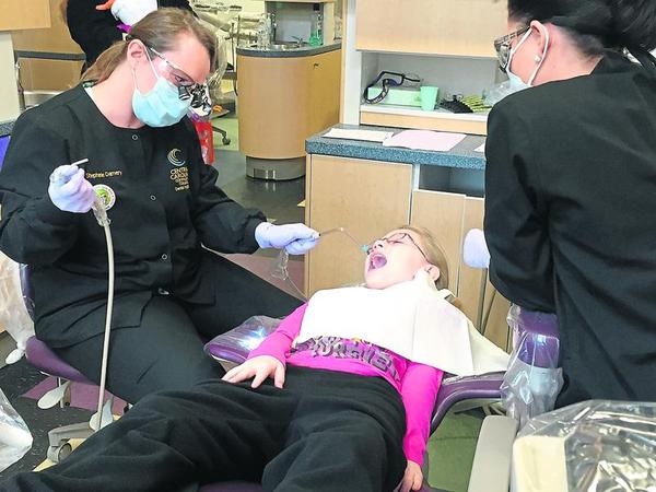 Click to enlarge,  Photo by Kathryn Trogdon at The Sanford Herald - Stephanie Damery of Central Carolina Community College cleans 9-year-old Sanford resident Julie Jamison&#8217;s teeth with what she calls &#8220;Mr. Squirty&#8221; and &#8220;Mr. Slurpy&#8221; to make the experience fun for children. 