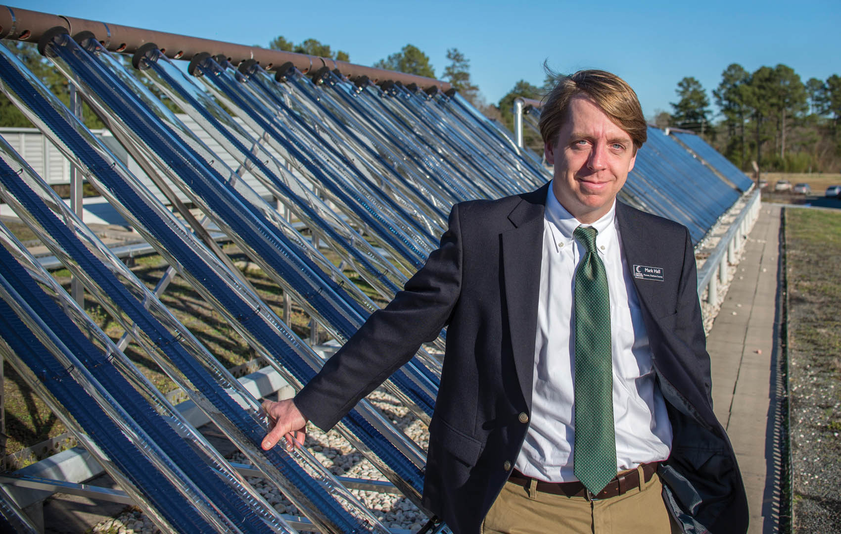 Click to enlarge,  Photo courtesy of The Sanford Herald. Mark Hall, Central Carolina Community College's Chatham County Provost, stands next to solar tubes used to heat water on CCCC's Pittsboro Campus. 