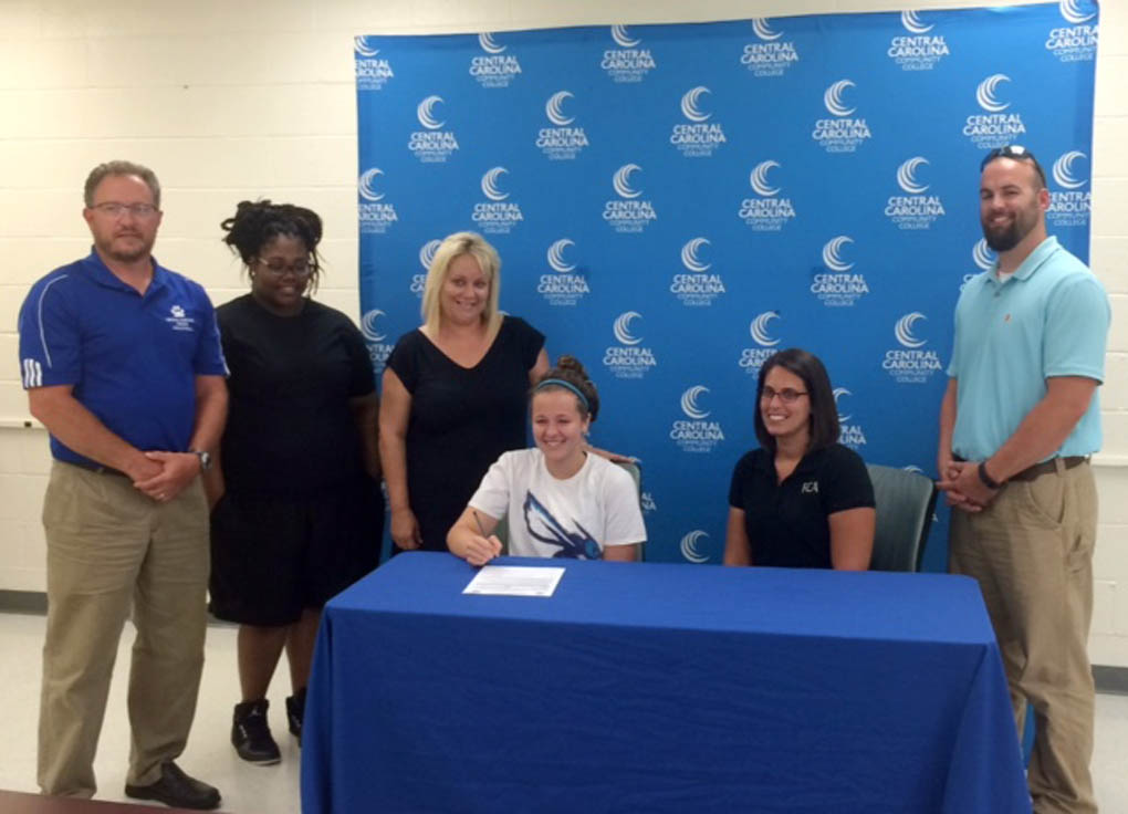 Click to enlarge,  Falcon Christian Academy's Brianna Roper, seated left, signed to attend and play volleyball at Central Carolina Community College. 
