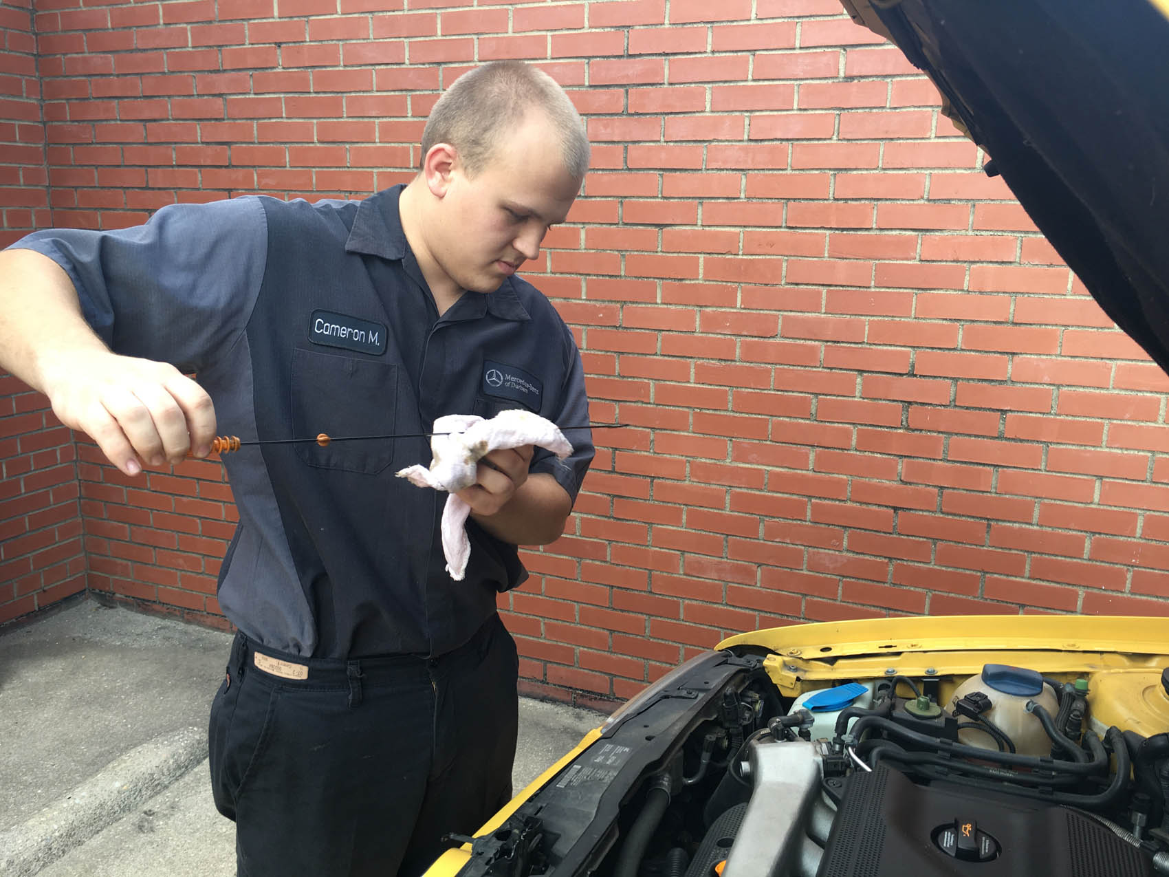 Click to enlarge,  Zachary Horner, The Sanford Herald. Cameron Miller, 20, of Sanford, checks a fluid level on his car. Miller graduated with an associate's degree from Central Carolina Community College a year-and-a-half ago and now works at Mercedes-Benz of Durham alongside his father Tom. 