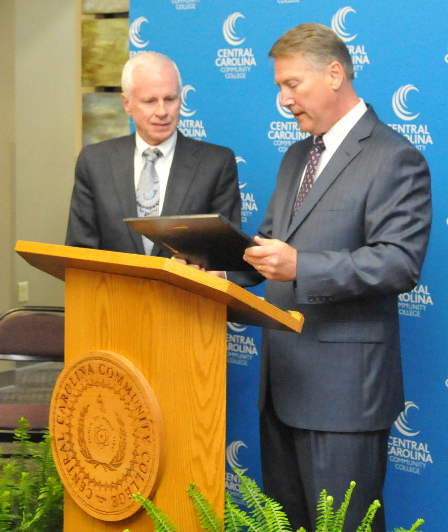 Click to enlarge,  Wayne Staton (left) receives the plaque honoring the naming of the Central Carolina Community College William W. and Ellen B. Staton Department of Paralegal Studies from former North Carolina Lt. Gov. Dennis Wicker (right), a friend of the Staton family who once served with William W. "Bill" Staton in the North Carolina General Assembly.  