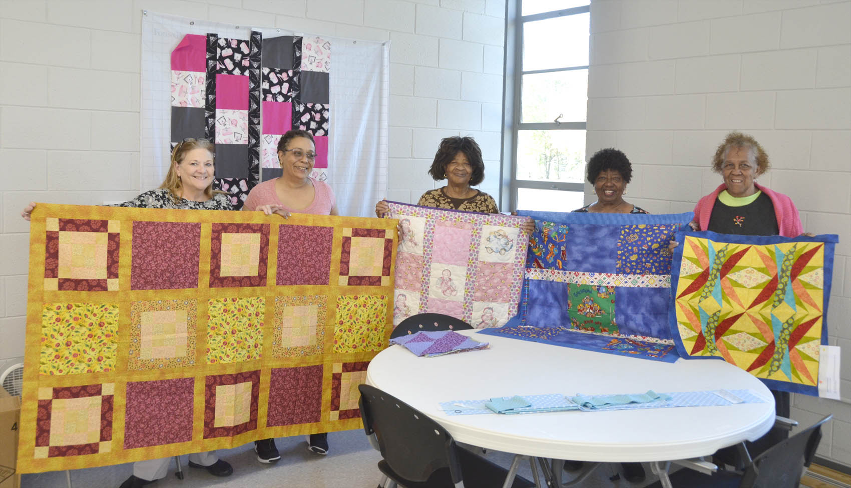 Click to enlarge,  Shaun Savarese | The Daily Record of Dunn. From left, Senior Activities Director Phyllis Taylor, quilt instructor Valerie Thompson, Mary Peterson, Betty McKoy and Annie McNeill present handmade quilts to be donated to victims of domestic violence.  