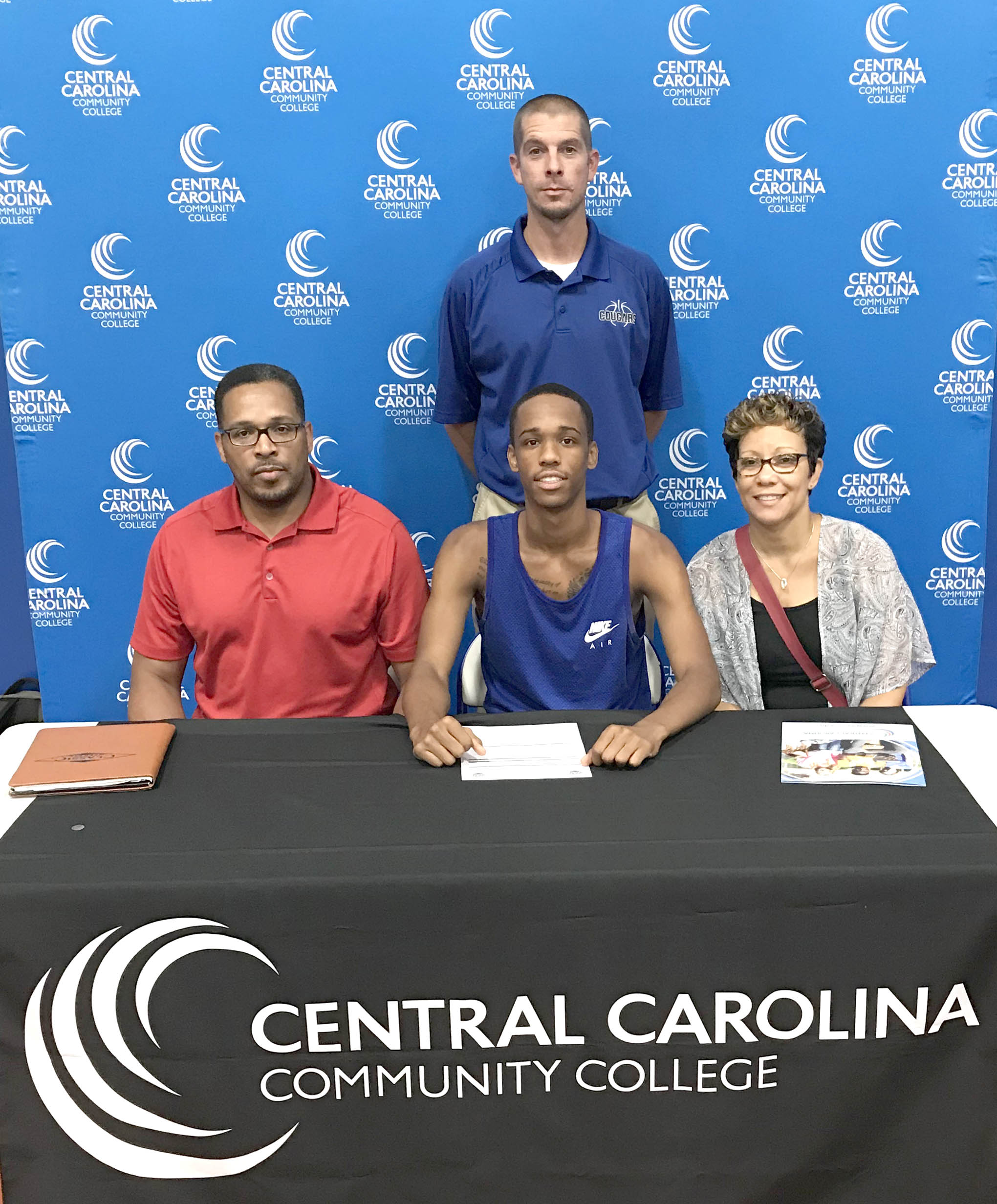 Click to enlarge,  Jackson Reid (seated center), of Panther Creek High School, Cary, recently announced his decision to join the Central Carolina Community College men's basketball program. 