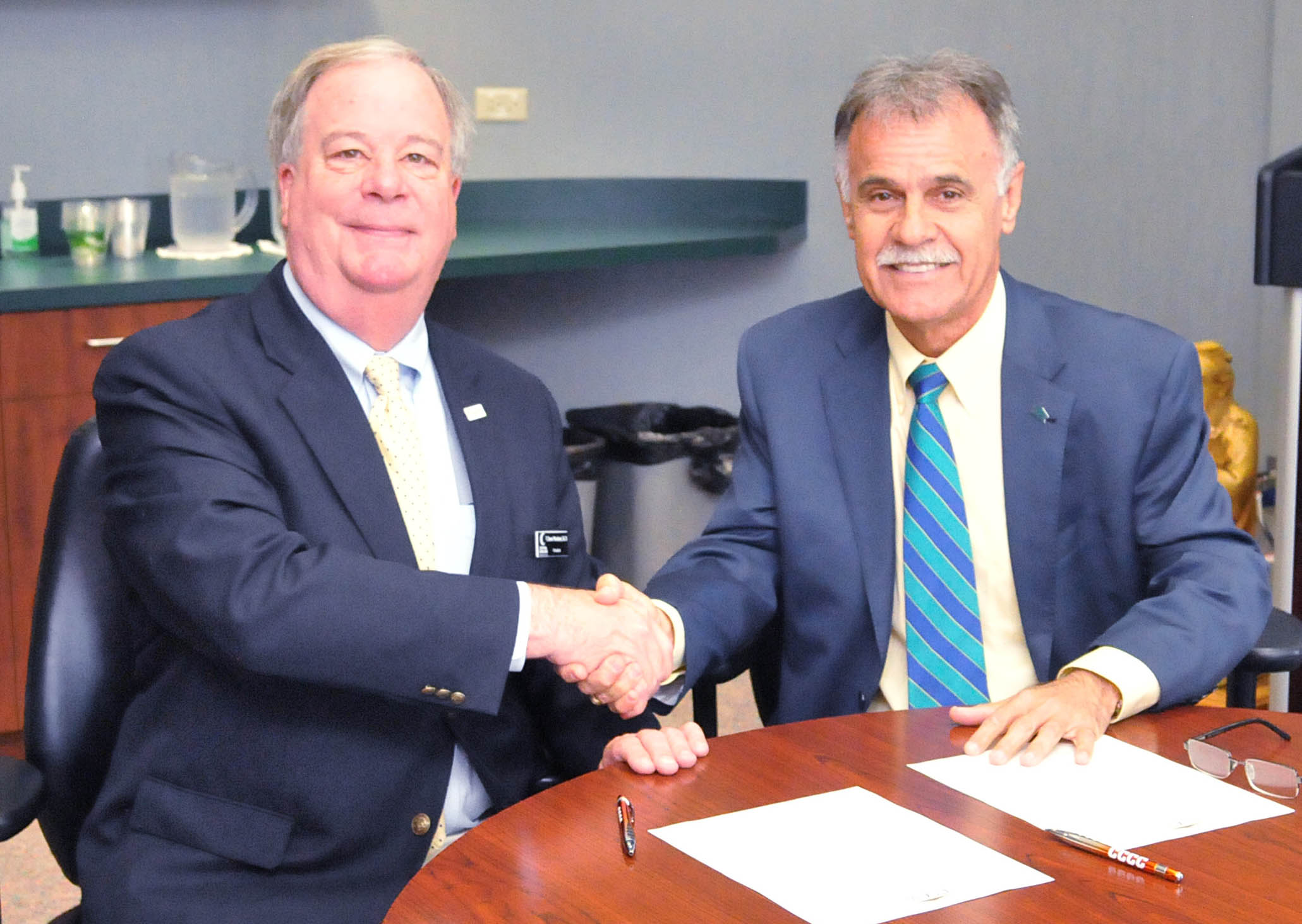 Click to enlarge,  Central Carolina Community College and The University of North Carolina Wilmington have agreed to a partnership called the Pathway to Excellence Program.  CCCC President Dr. T. Eston Marchant (left) and UNCW Chancellor Jose V. Sartarelli shake hands after signing the agreement. 