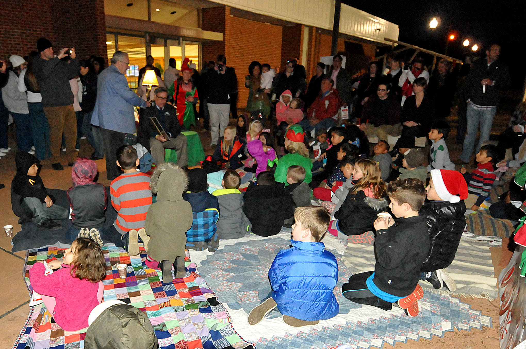 Click to enlarge,  Children gathered around Julian Philpott, Central Carolina Community College Board of Trustees Chairman, listening eagerly as he read Clement Moore's holiday classic, "'Twas the Night Before Christmas," at the CCCC Foundation Christmas Tree Lighting celebration. 