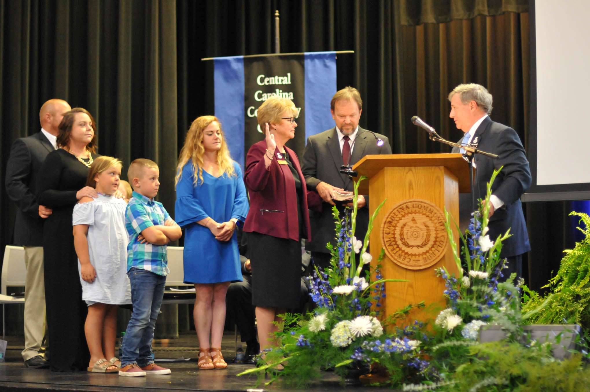 Click to enlarge,  Central Carolina Community College President Dr. Lisa M. Chapman receives the Oath of Office from Julian Philpott, Chairman of the CCCC Board of Trustees, as Dr. Chapman's family joins her on stage for her Installation as CCCC President on Sept. 26. 