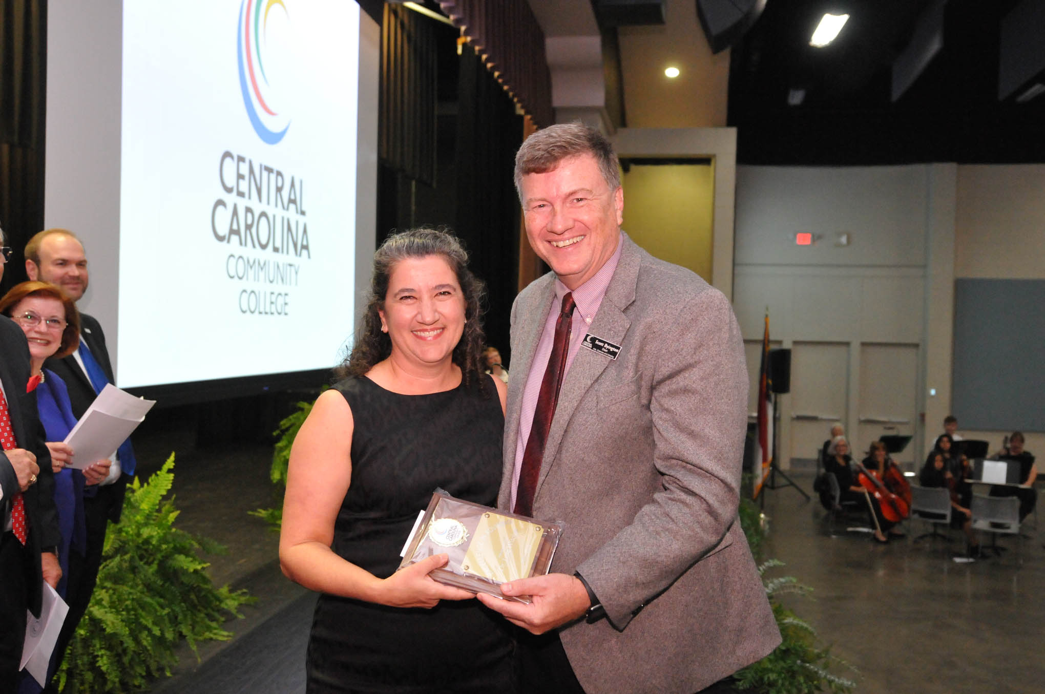 Click to enlarge,  Dr. Lora Witcher (left) receives the Central Carolina Community College Advisor of the Year award from Scott Byington (right), CCCC Dean of Arts, Sciences and Advising, during the Convocation and Installation of Dr. Lisa M. Chapman as Sixth President of CCCC on Sept. 26. 