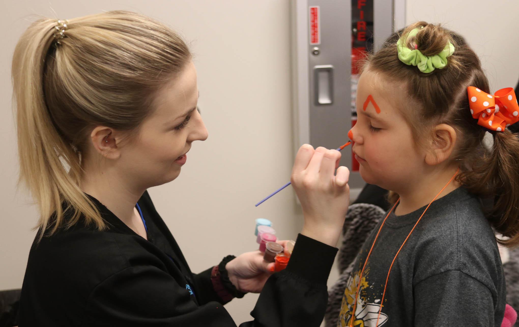 Click to enlarge,  A Central Carolina Community College Dental Hygiene student provides face painting to a student. 