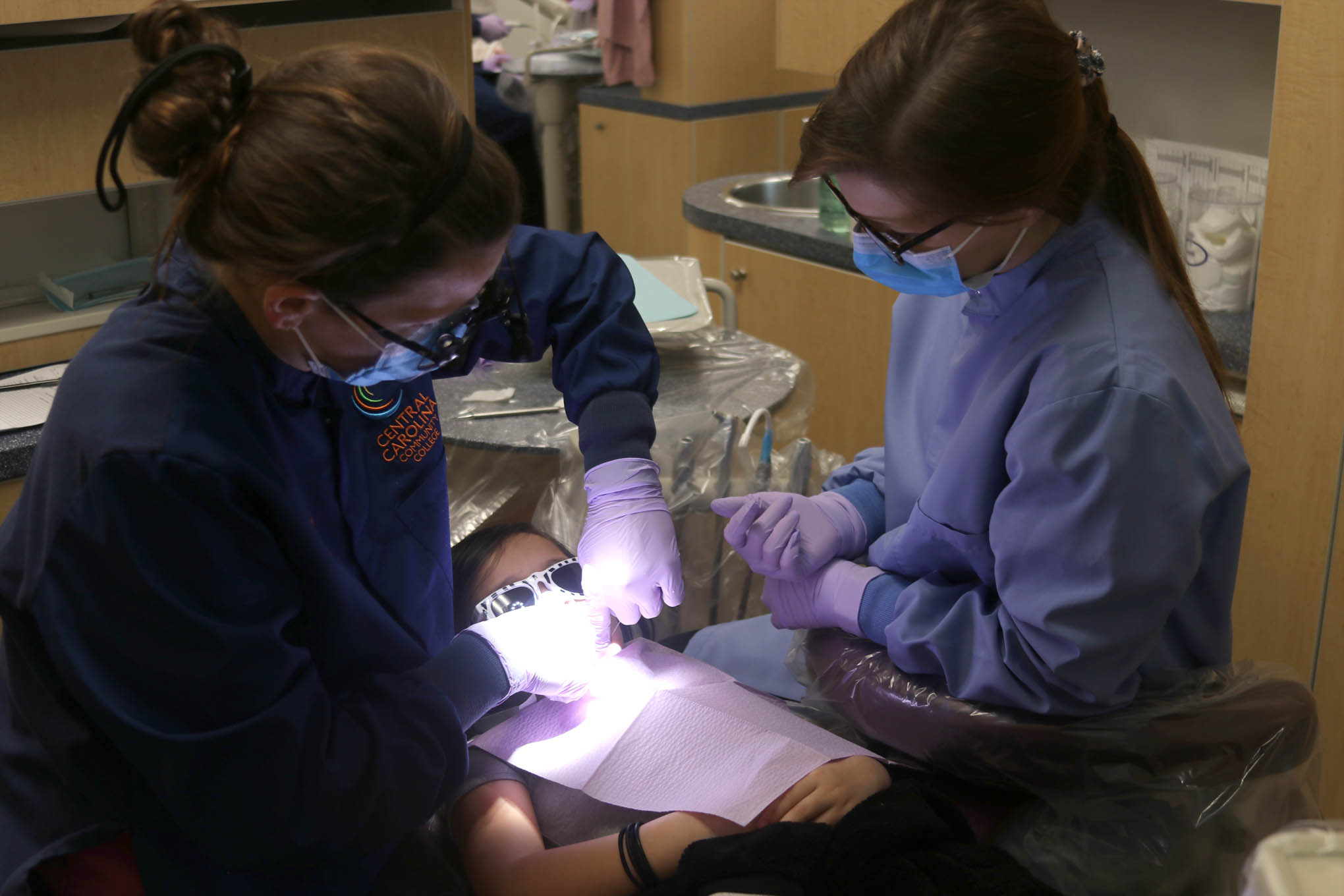Click to enlarge,  Central Carolina Community College Dental Hygiene and Dental Assisting students apply sealants to a student. 