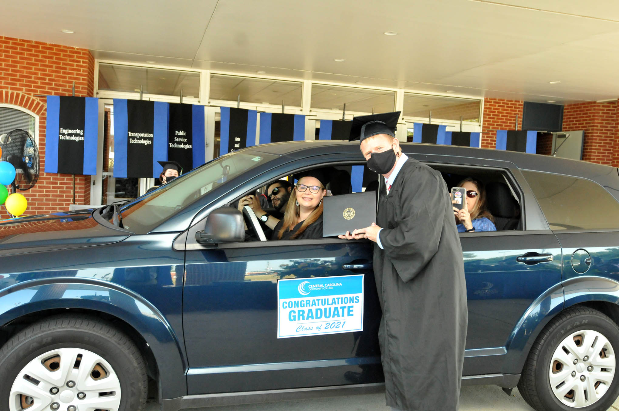 Click to enlarge,  Central Carolina Community College Executive Vice President / Chief Financial Officer Dr. Phillip Price visits with one of the new CCCC graduates. Each student was given a vehicle magnet signifying his/her graduation from the college. 