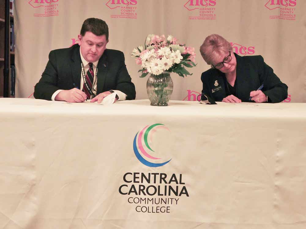 Click to enlarge,  Harnett County Schools Superintendent Dr. Aaron L. Fleming and Central Carolina Community College President Dr. Lisa M. Chapman (right) sign an agreement for the formation of the Harnett Agriculture Academy. The signing ceremony was held Wednesday, Feb. 23, at Triton High School in Erwin, N.C. 