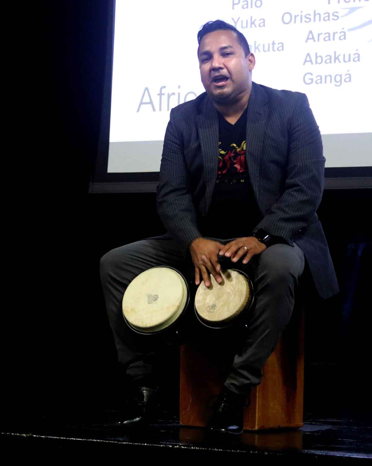 Click to enlarge,  Norberto "Betto" Herrera taps out some rhythms on the bongos during his presentation at Central Carolina Community College explaining the evolution of salsa music. 