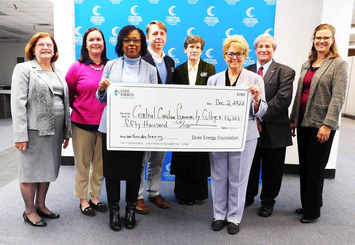 Click to enlarge,  Indira Everett (front left), Duke Energy Director for the East region, presents a $50,000 check for workforce development training to Dr. Lisa M. Chapman (front right), Central Carolina Community College President. Standing behind are, left to right: Lynda Turbeville, Chair of the CCCC Foundation Board of Directors; Dr. Emily C. Hare, CCCC Foundation Executive Director; Dr. Mark Hall, CCCC Chatham County Provost; Margaret Roberton, CCCC Vice President for Workforce Development; Julian Philpott, Chair of the CCCC Board of Trustees; and Kelly Klug, CCCC Director of Grants Development. 