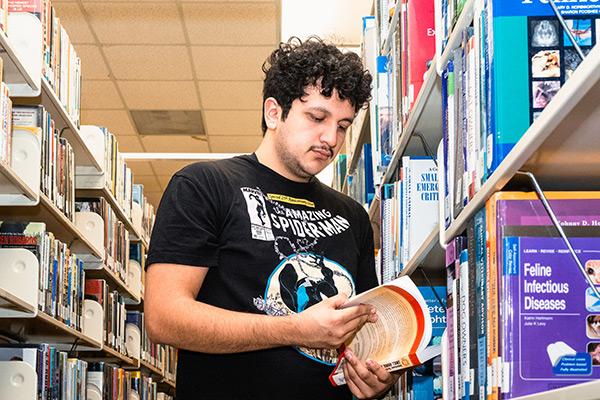 Student in library flipping through book