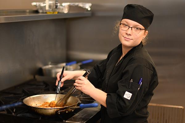 Smiling student in the culinary kitchen cooking 