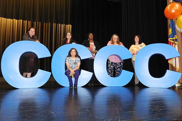 College employees gathered around large letters spelling CCCC