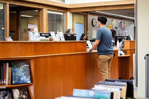 Student at library desk checking out book