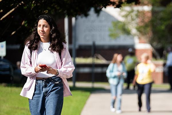 Student walking through campus with phone in hand