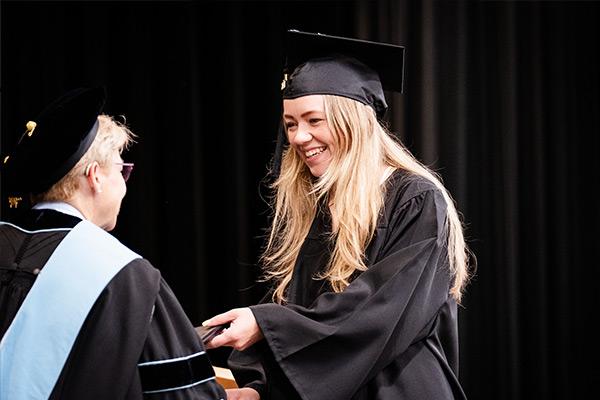 Student walking across stage accepting diploma 