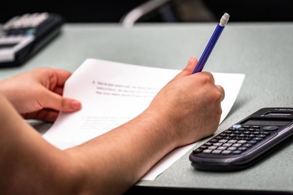 Students hands with paper & calculator 